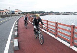 Rider riding on the bike path between the riverside and the road